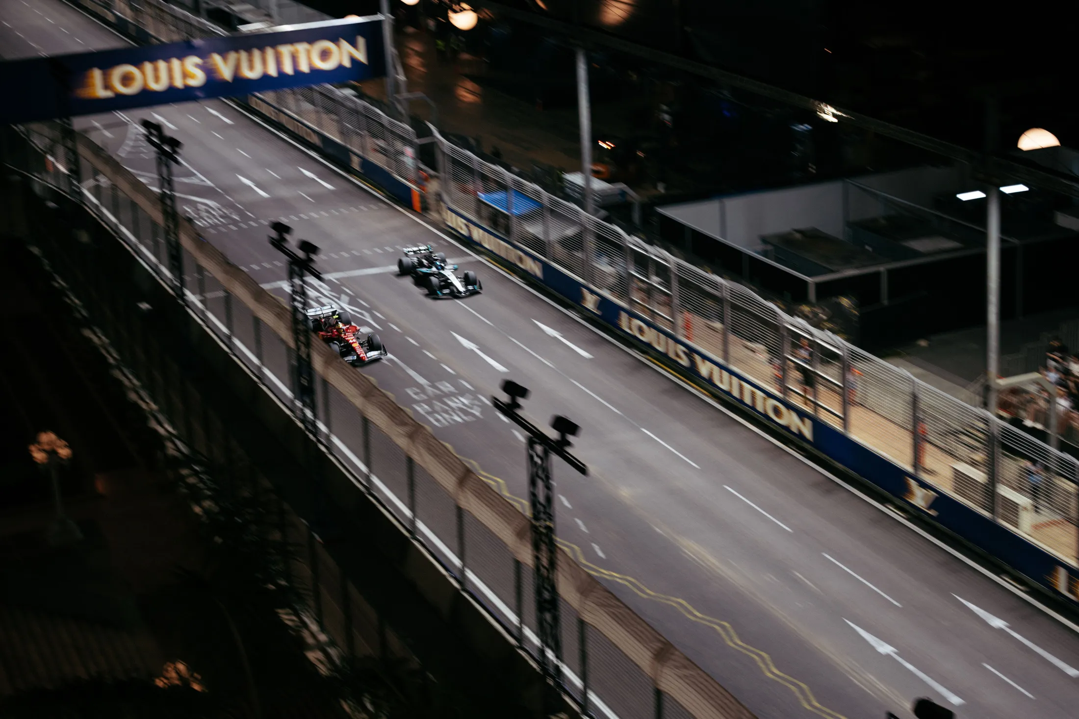 Formula 1 cars beneath the Louis Vuitton bridge on the Marina Bay Street Circuit, seen from the 47A® position